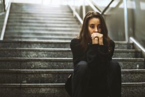Martwiąca się kobieta siedzi na schodach. Jak przestać się martwić i zacząć normalnie żyć?