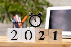 Drewniane kostki z rokiem 2021, budzik i laptop. Jak się nie zniechęcać i zrealizować noworoczne postanowienie?