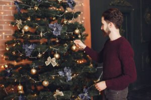 Mężczyzna przystraja choinkę. Samotne święta w czasie pandemii - jak je przeżyć?