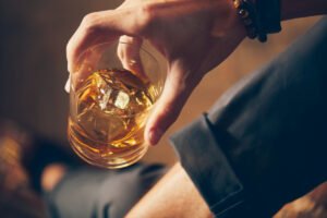 Mężczyzna trzyma szklankę z whisky. Objawy alkoholizmu - sprawdź, zanim wszystko stracisz
