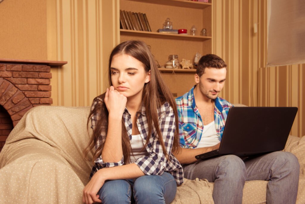 Mężczyzna serfuje po internecie i ignoruje swoją partnerkę. Samotność w związku — jak do niej dochodzi