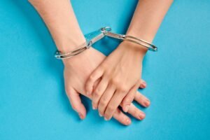 Trzymające się ręcę w kajdankach na niebieskim tle - Współuzależnienie – jak sobie z nim radzić