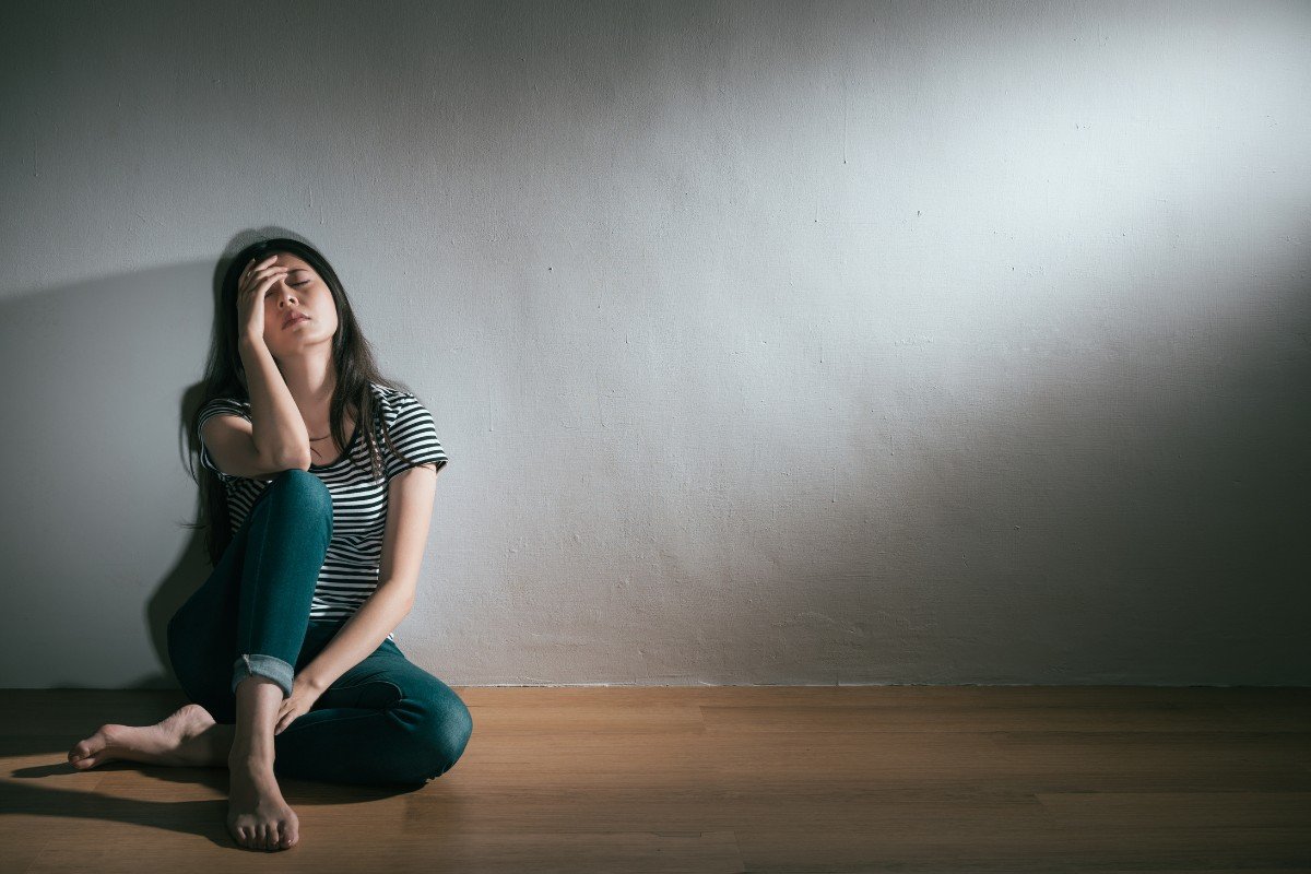 Objawy maniakalno-depresyjne - kobieta siedząca pod ścianą