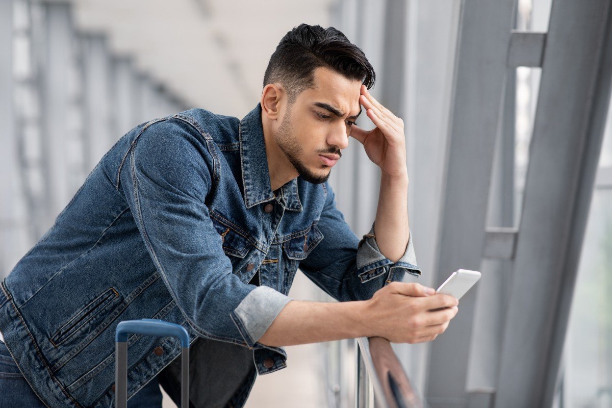 Mężczyzna na lotnisku korzysta z wolnej chwili, by przeglądać telefon