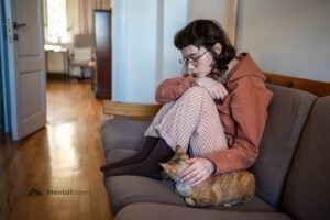 Smutna kobieta siedząca z kotem na sofie - anhedonia