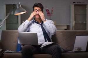 Mężczyzna pracuje po godzinach w domu. Pracoholizm objawy
